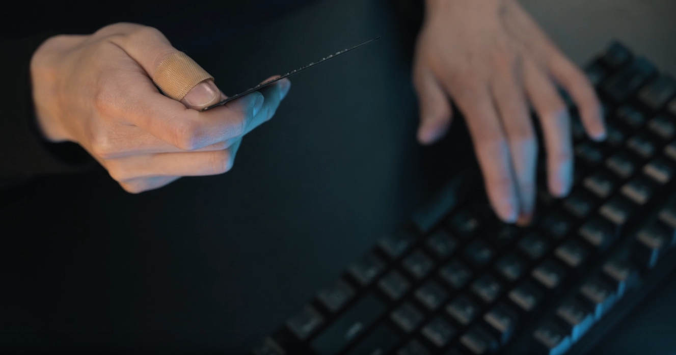 A person using a computer while holding a card, representing a personalized digital experience